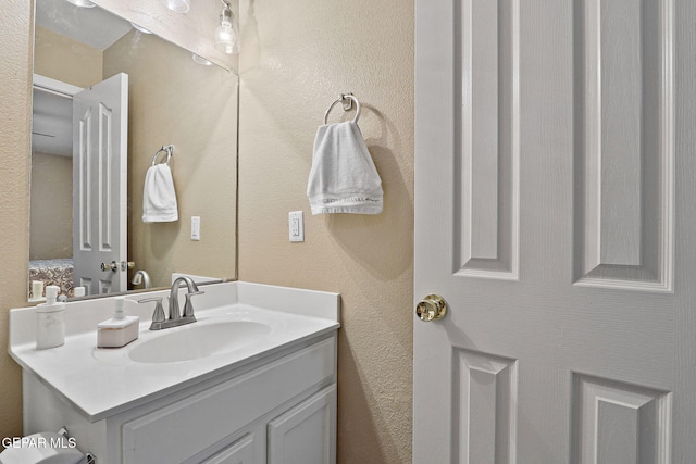 bathroom featuring a textured wall and vanity