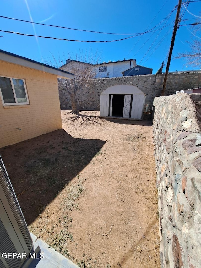 view of yard with a shed, fence, and an outbuilding