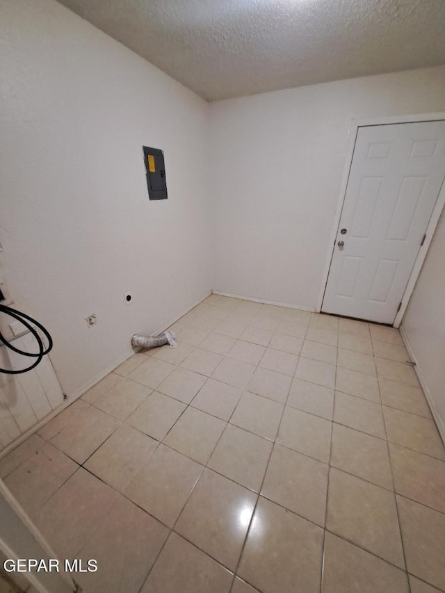 unfurnished room featuring electric panel, a textured ceiling, and light tile patterned floors