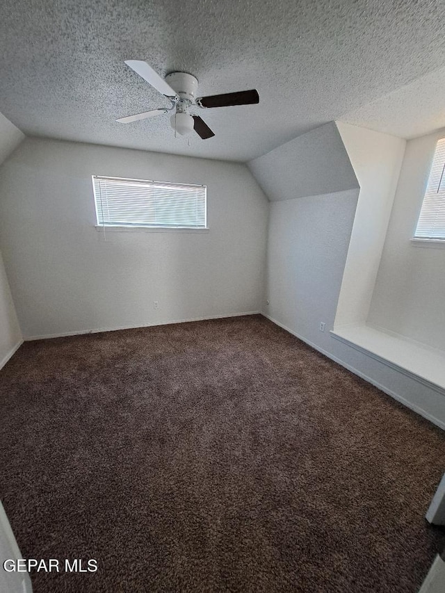 bonus room with carpet floors, vaulted ceiling, a textured ceiling, and ceiling fan