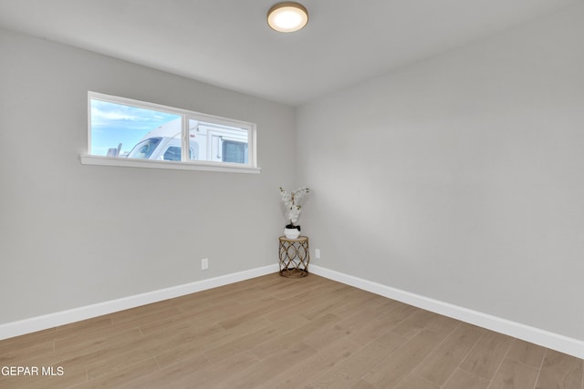 unfurnished room with baseboards and light wood-style floors