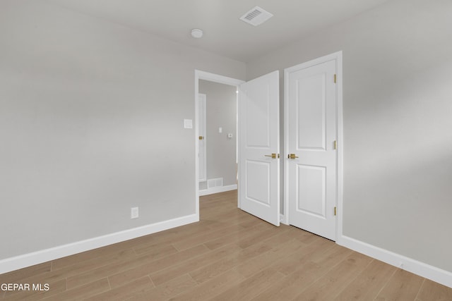 unfurnished bedroom with light wood-style floors, visible vents, and baseboards