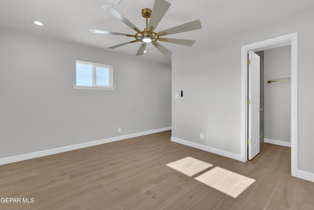 unfurnished bedroom with a walk in closet, recessed lighting, light wood-style flooring, a ceiling fan, and baseboards