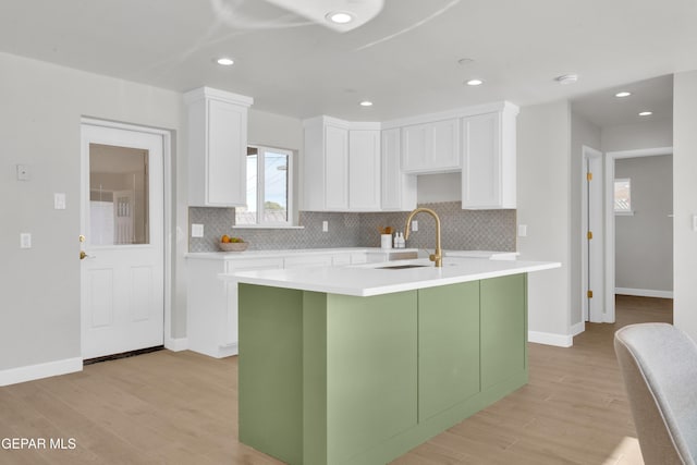 kitchen with light wood-type flooring, light countertops, a sink, and white cabinetry