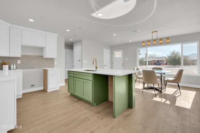 kitchen with light countertops, green cabinetry, a sink, and white cabinetry