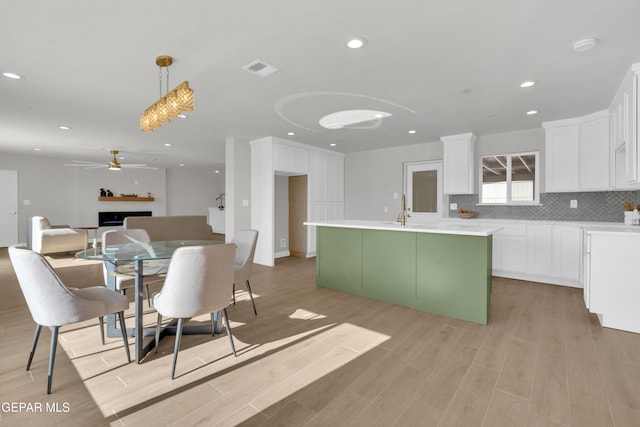 kitchen featuring tasteful backsplash, open floor plan, hanging light fixtures, light countertops, and white cabinetry