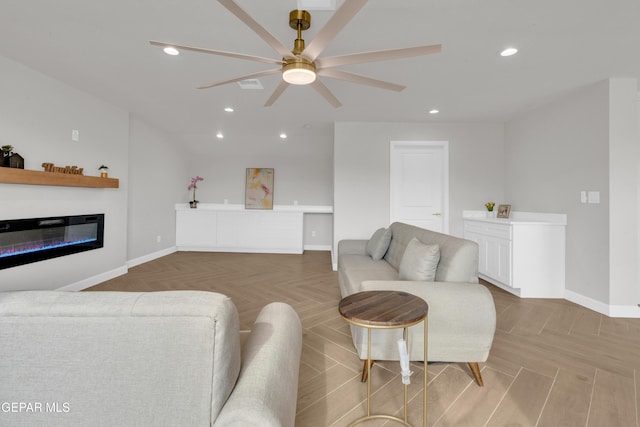 living room featuring a ceiling fan, a glass covered fireplace, parquet floors, and recessed lighting