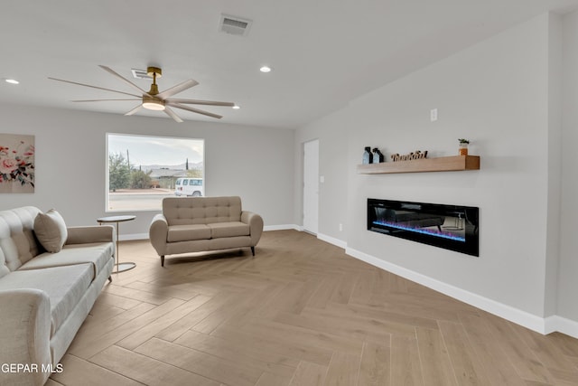 living area featuring recessed lighting, visible vents, a glass covered fireplace, ceiling fan, and baseboards