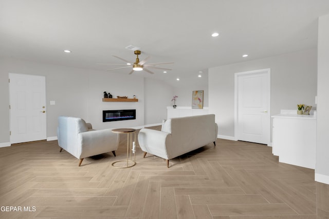 living area featuring a glass covered fireplace, ceiling fan, baseboards, and recessed lighting