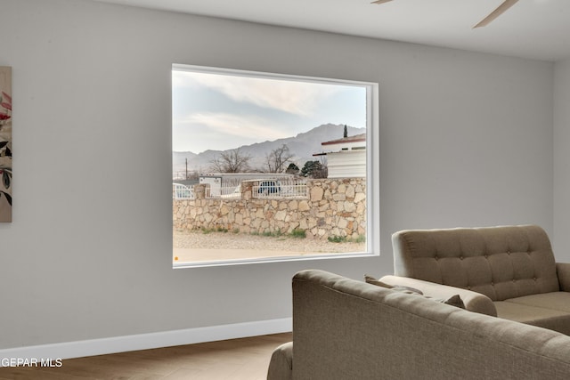 sitting room with light wood finished floors, baseboards, a mountain view, and a ceiling fan