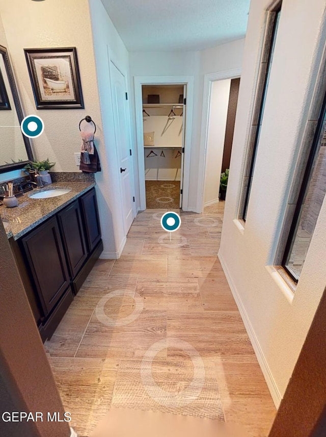 hallway with a sink, light wood-style flooring, and baseboards