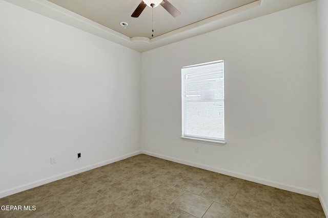 unfurnished room with a ceiling fan, a tray ceiling, and baseboards