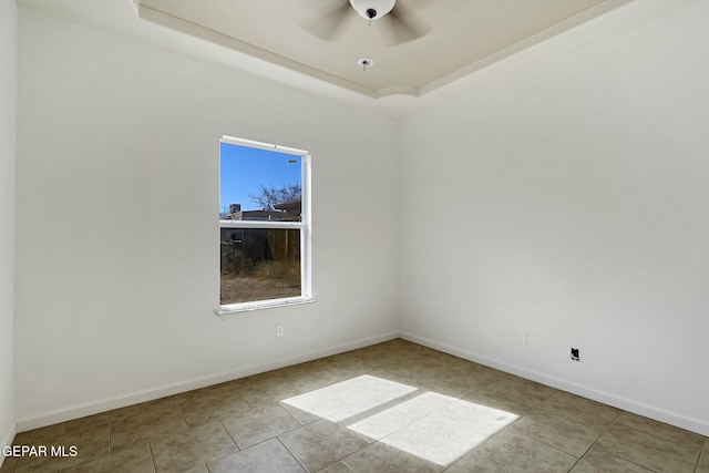 spare room featuring a raised ceiling, ceiling fan, baseboards, and light tile patterned floors