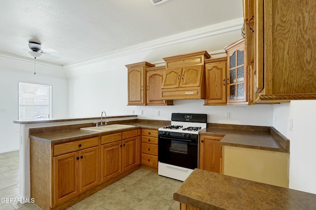 kitchen with brown cabinetry, dark countertops, range with gas cooktop, and glass insert cabinets