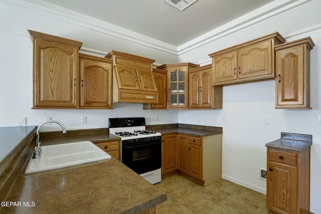 kitchen with range with gas stovetop, dark countertops, and a sink