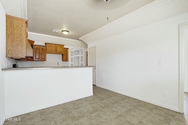 kitchen featuring a sink, visible vents, light countertops, brown cabinets, and crown molding