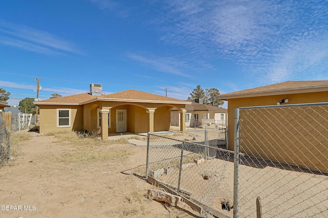 back of house featuring a fenced front yard and stucco siding