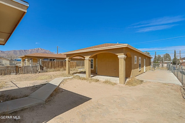 back of house featuring a mountain view, fence, and stucco siding