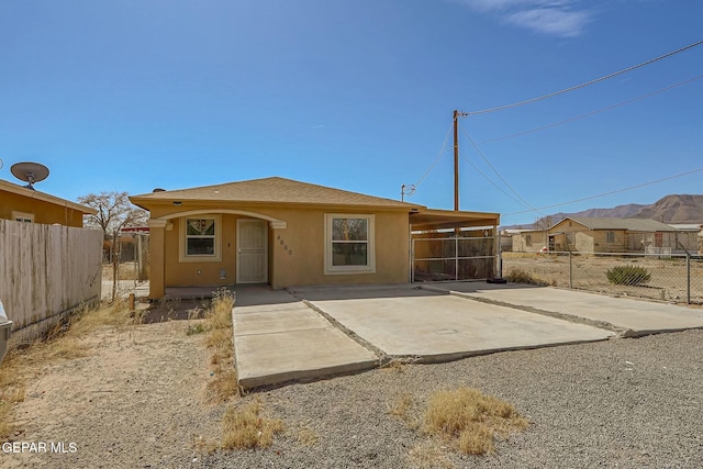 rear view of property featuring a patio, fence, and stucco siding