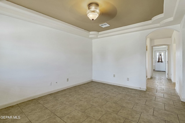 spare room featuring arched walkways, light tile patterned flooring, visible vents, baseboards, and a raised ceiling