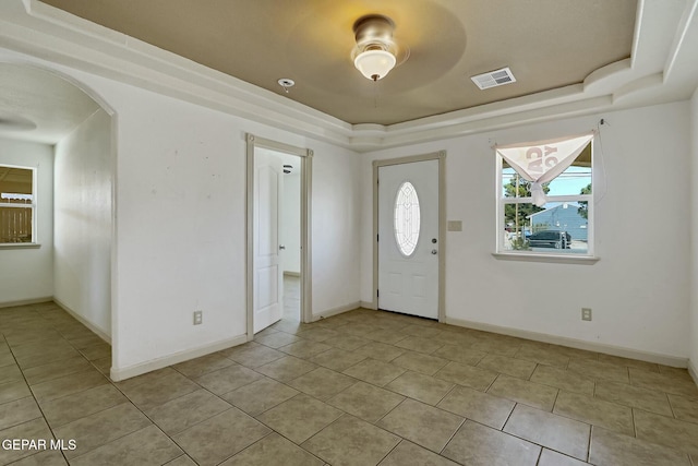 entryway with arched walkways, a tray ceiling, light tile patterned flooring, and visible vents