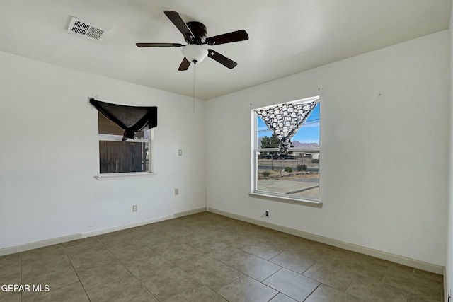 spare room featuring ceiling fan, visible vents, and baseboards