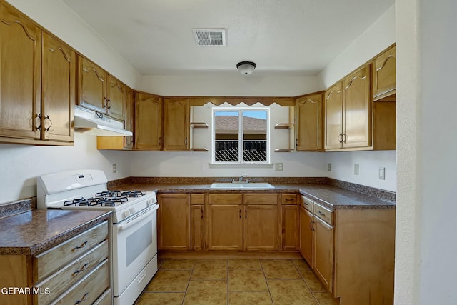 kitchen with under cabinet range hood, a sink, visible vents, gas range gas stove, and dark countertops