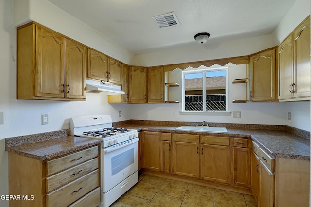 kitchen featuring white gas range oven, visible vents, dark countertops, under cabinet range hood, and a sink