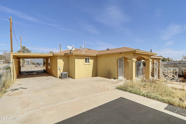 view of front of property with cooling unit, fence, concrete driveway, stucco siding, and a carport