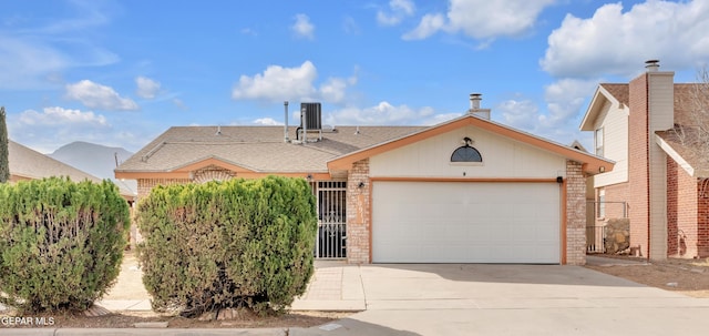 ranch-style home with concrete driveway, brick siding, an attached garage, and central air condition unit