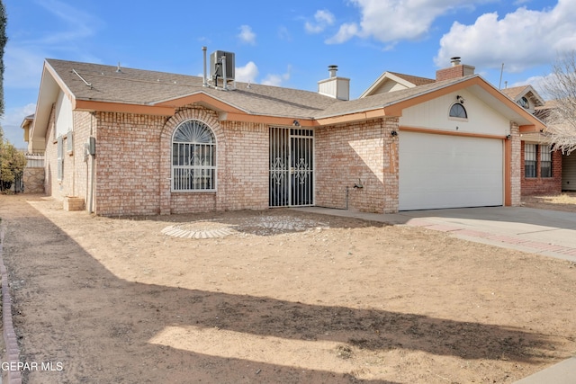 single story home featuring a garage, brick siding, driveway, and central air condition unit