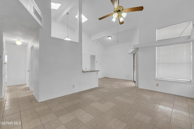 unfurnished room featuring high vaulted ceiling, a skylight, visible vents, a ceiling fan, and beam ceiling