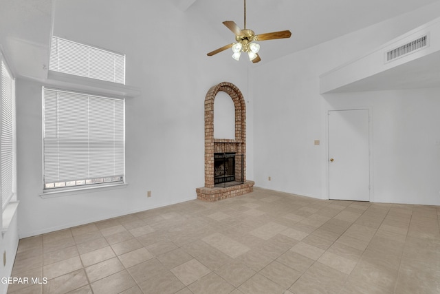 unfurnished living room with visible vents, a fireplace, a towering ceiling, and ceiling fan