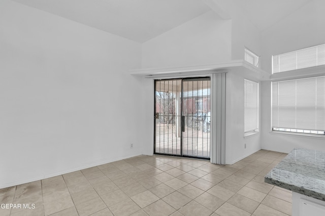 empty room with baseboards, high vaulted ceiling, and light tile patterned flooring