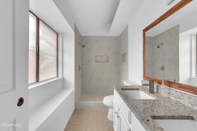 bathroom with double vanity, toilet, tile patterned floors, a tile shower, and a sink