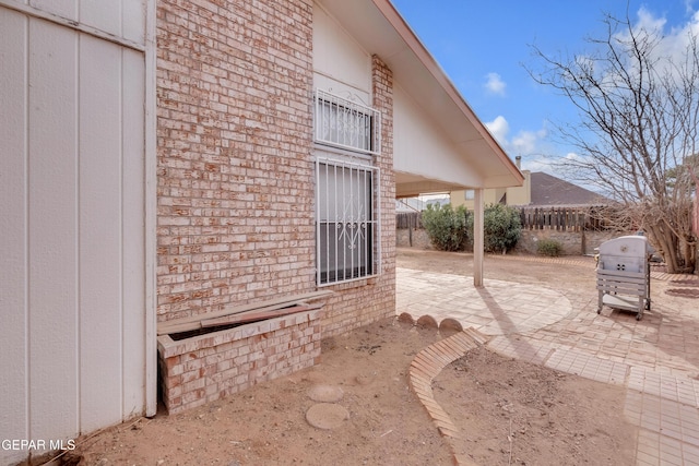 exterior space with brick siding, a patio area, and fence