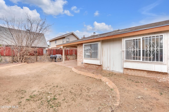 rear view of property featuring a patio, brick siding, and fence