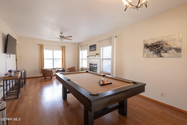 rec room featuring a ceiling fan, baseboards, wood finished floors, and a glass covered fireplace