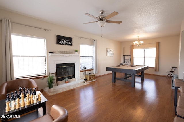 game room featuring baseboards, ceiling fan with notable chandelier, wood finished floors, and a high end fireplace