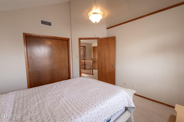 bedroom with lofted ceiling, visible vents, baseboards, a closet, and carpet