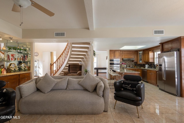 living area with a ceiling fan, light tile patterned floors, visible vents, and stairs