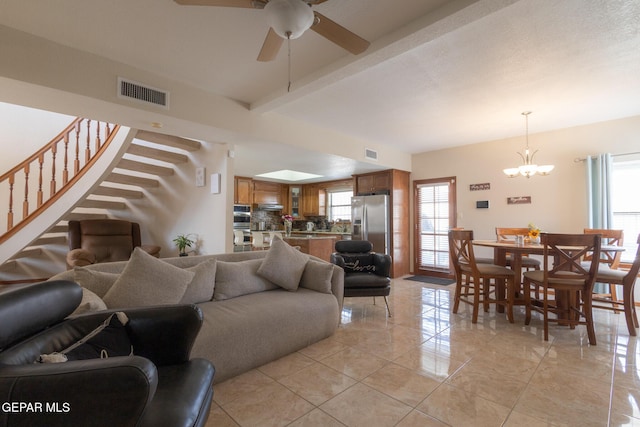 living room with a healthy amount of sunlight, visible vents, stairway, and ceiling fan with notable chandelier