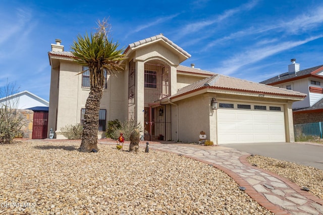 mediterranean / spanish house with a garage, driveway, a tiled roof, and stucco siding