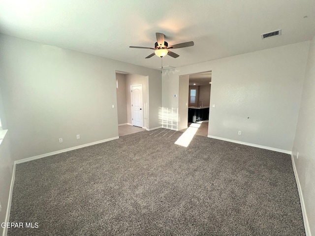 carpeted spare room featuring a ceiling fan, visible vents, and baseboards