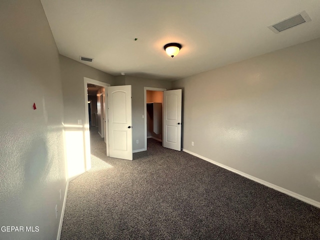 unfurnished bedroom with baseboards, visible vents, and dark colored carpet