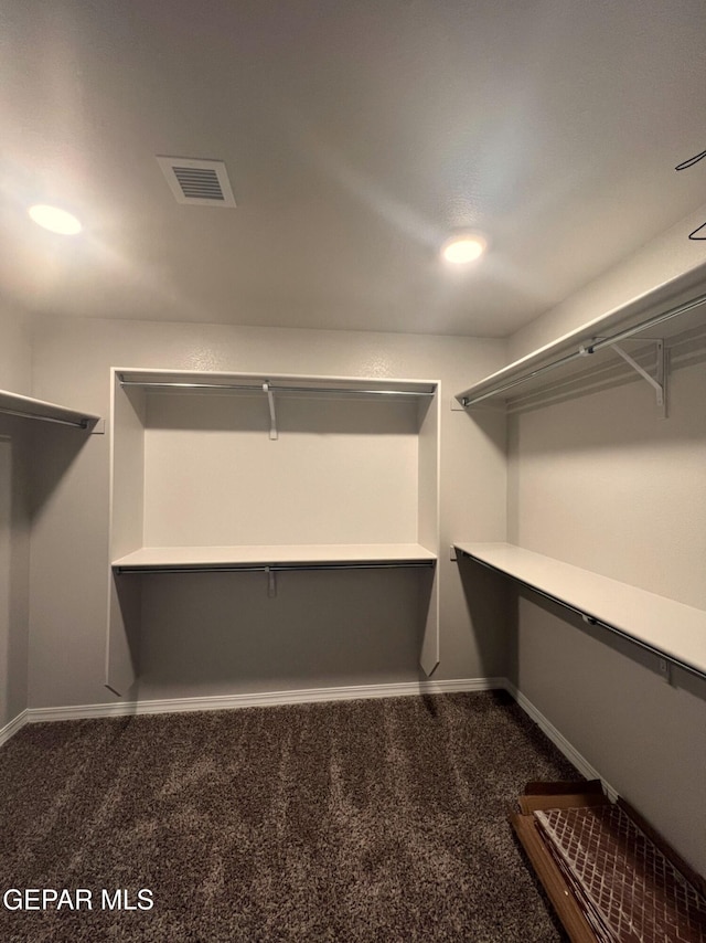 spacious closet featuring dark carpet and visible vents