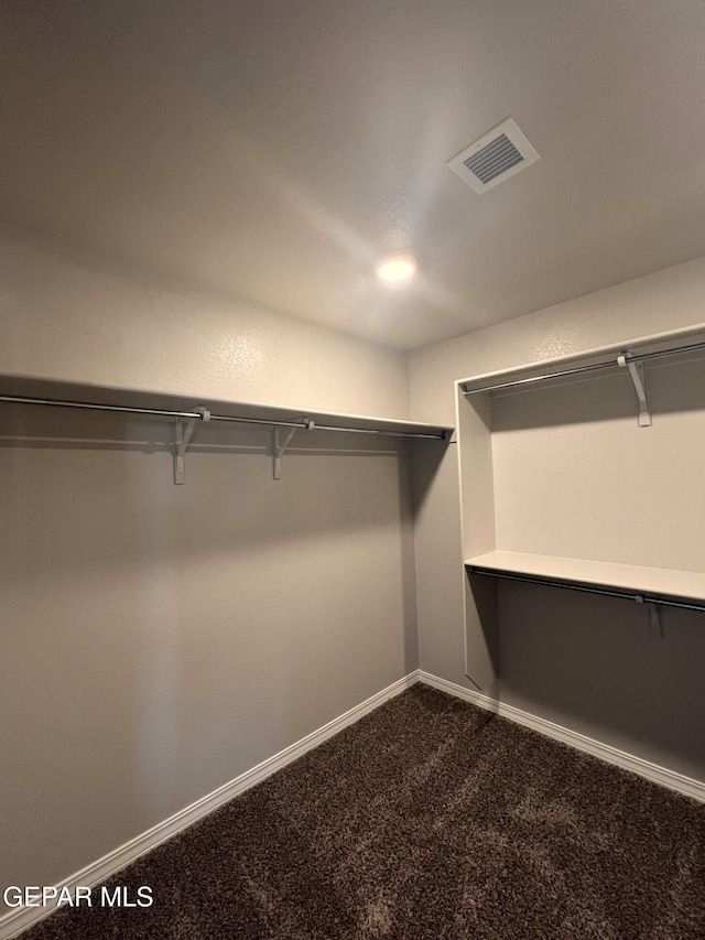 spacious closet with visible vents and dark carpet