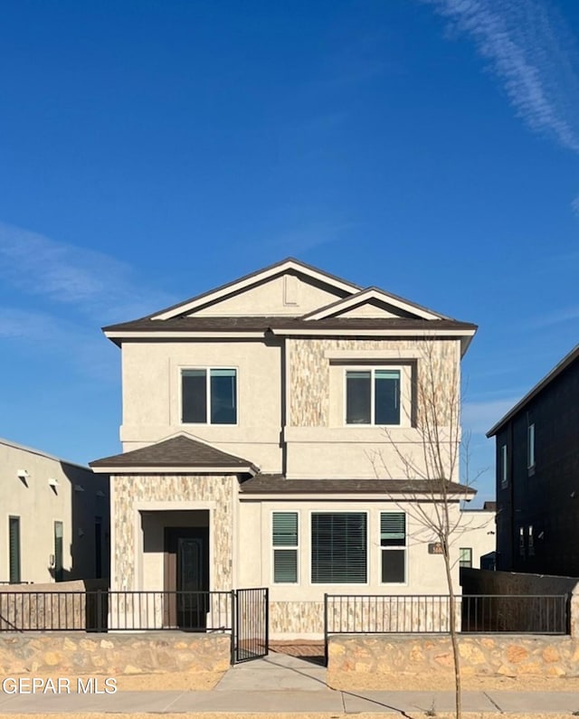 view of front facade featuring stone siding, a fenced front yard, and stucco siding