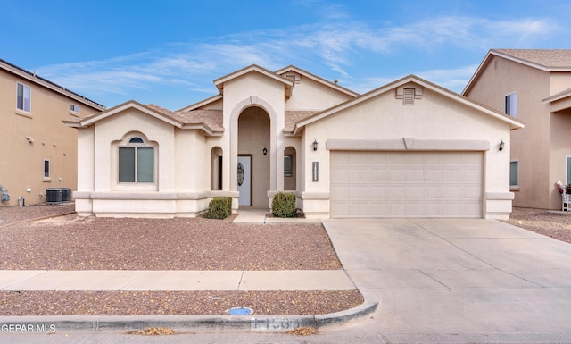 mediterranean / spanish home with concrete driveway, central AC, an attached garage, and stucco siding