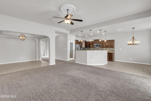 unfurnished living room featuring light carpet, light tile patterned floors, arched walkways, and ceiling fan with notable chandelier